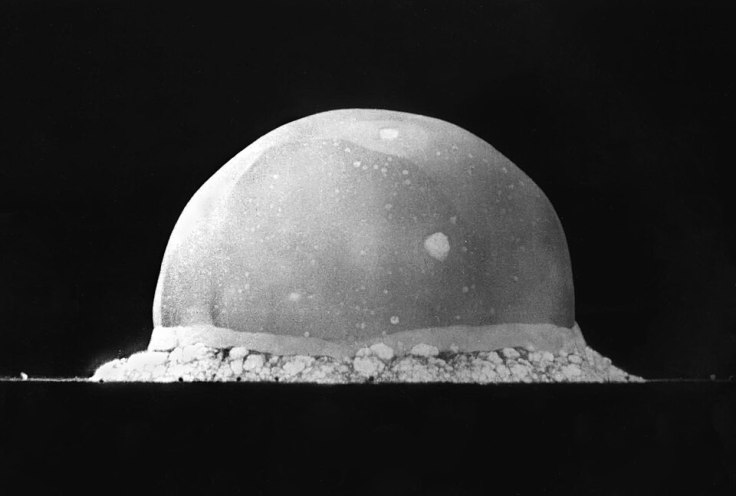 The Trinity fireball photographed 0.016 seconds after detonation, a glowing dome on the desert floor.